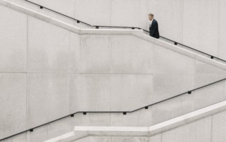 A man in a suit walks up an angular stairwell